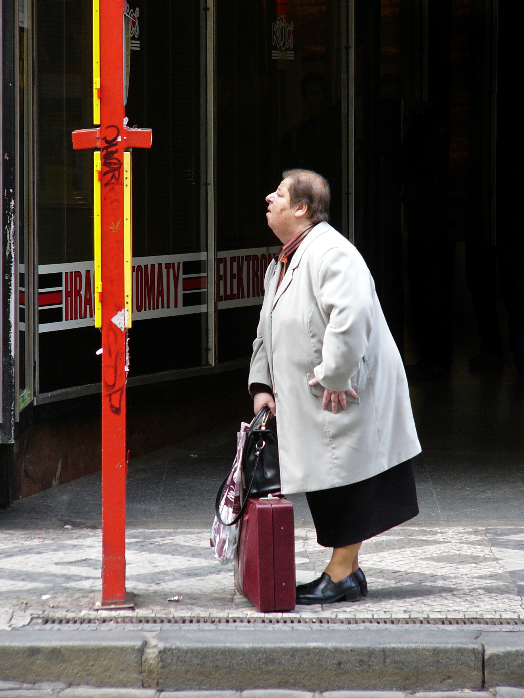 A passenger reading a posted tram timetable at a Prague stop